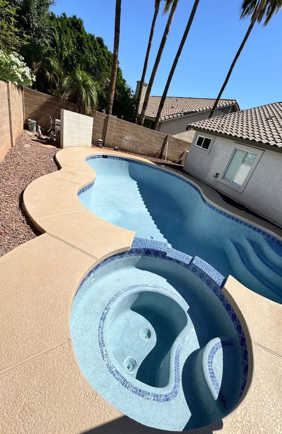 Freeform pool and round spa with blue tile