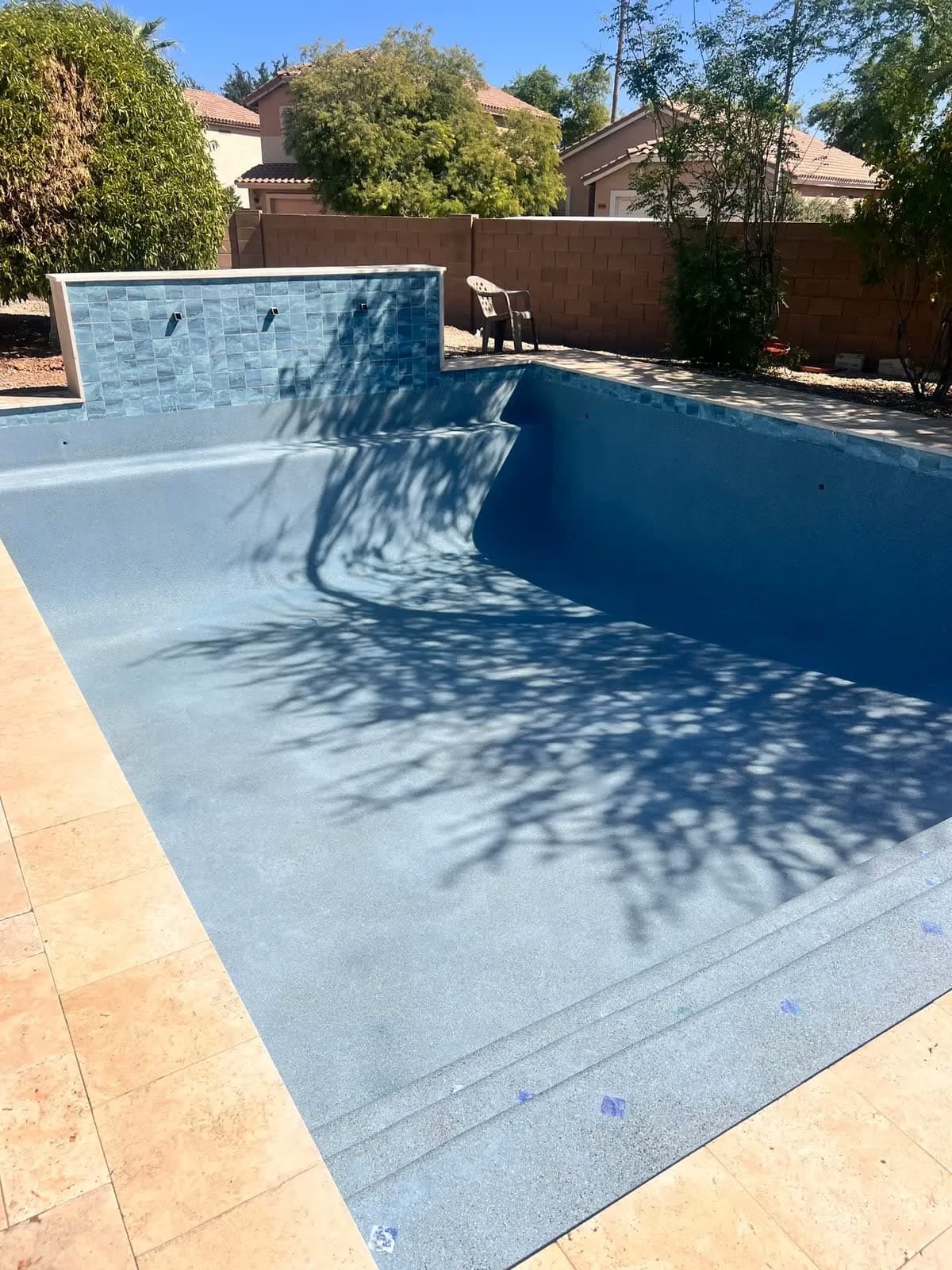 Empty pool with a fresh blue finish and a raised stone wall feature