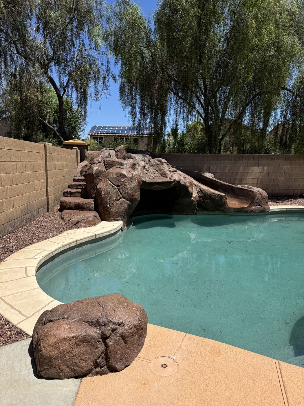 A backyard pool with a rock slide and grotto